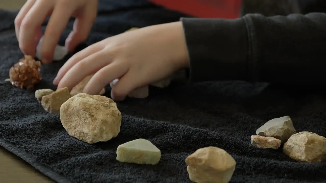 Top down view of a kid moving rocks around on a towel