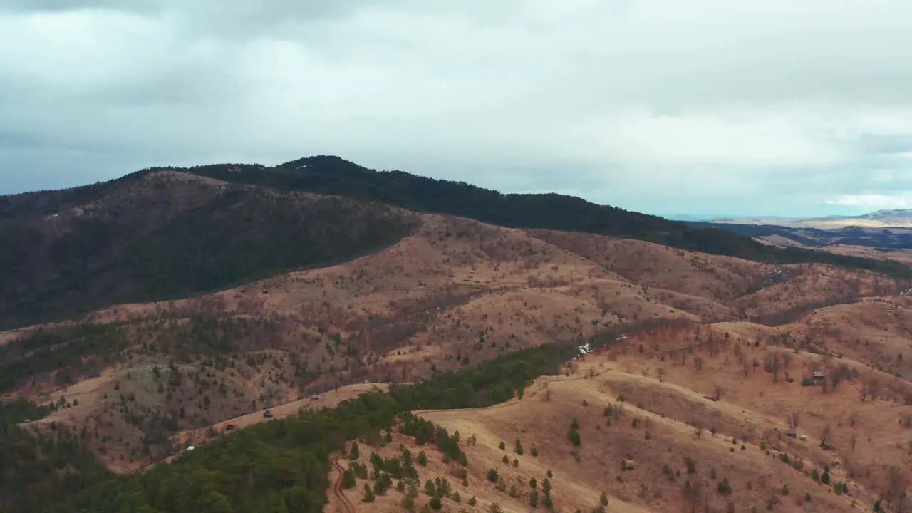 Aerial flyover shot of a temperate mountain range on a cloudy day