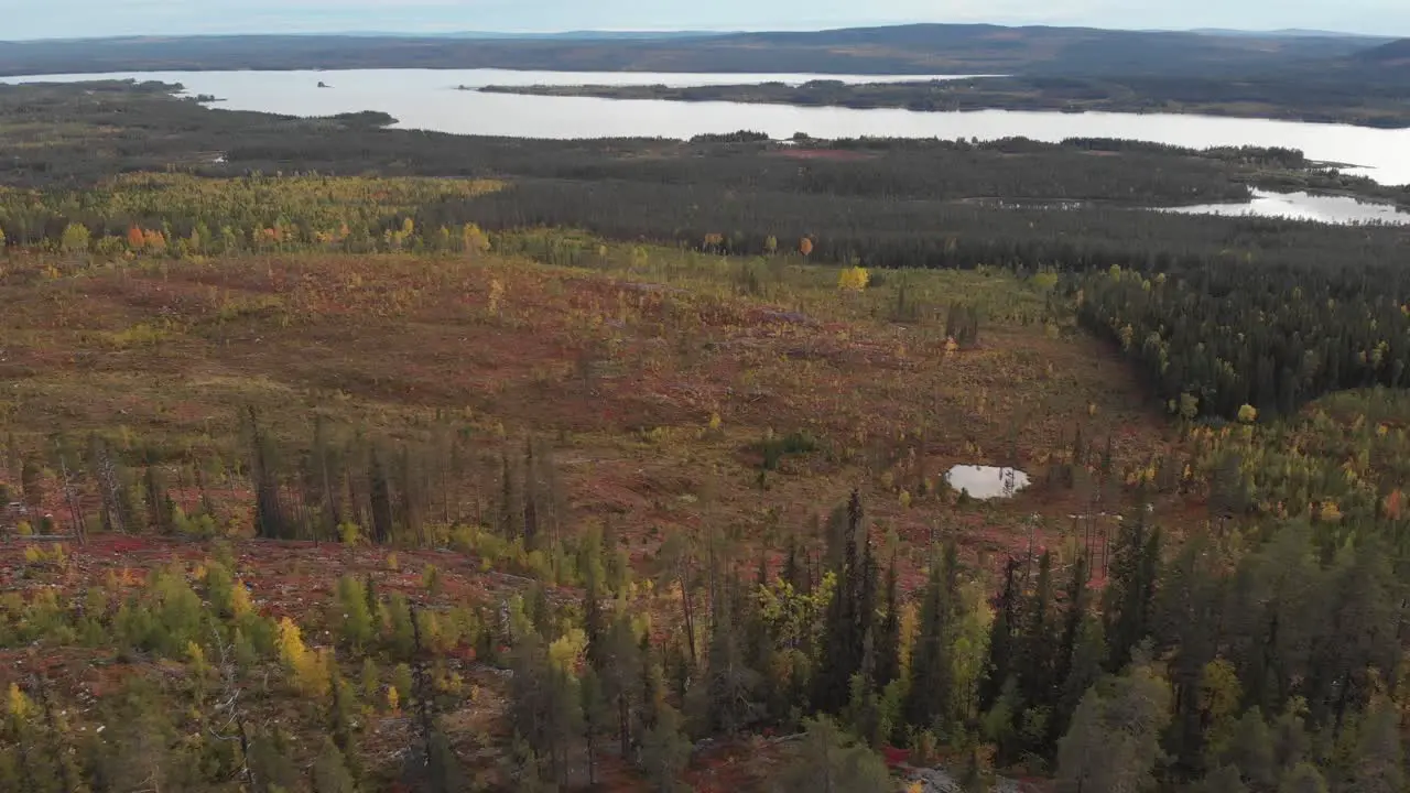 Aerial slow moving survey wide shot of mountainous terrain devoid of trees and forestation with a barren and sterile surrounding with a river tearing the horizon in Lapland Sweden