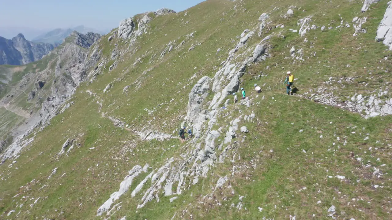 Aerial of group of climbers walking past a ledge on a high and rough mountain