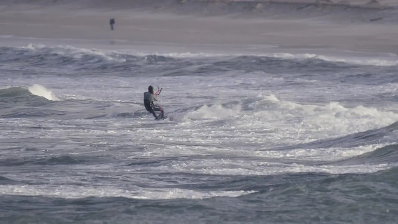 Kiteboarding is popular water sport for windy weather kiteboarder jumping on big waves in Peniche Portugal