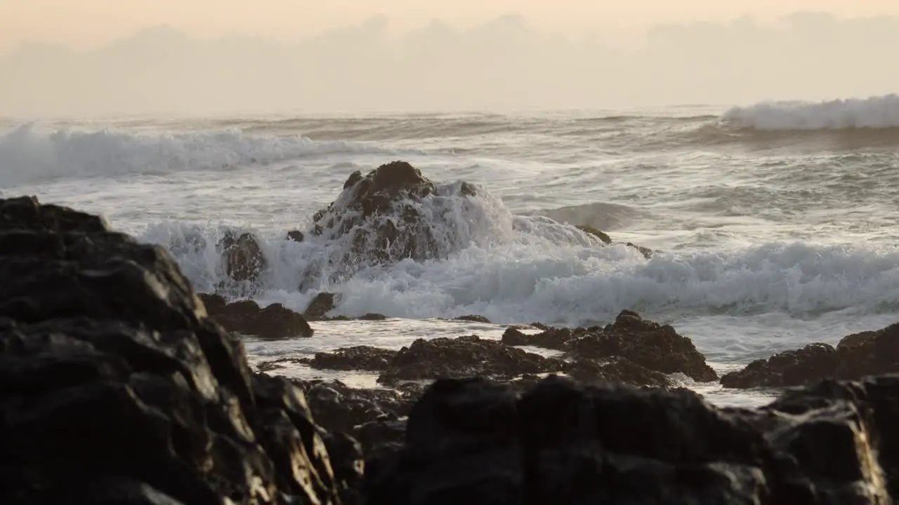 ocean waves slowly crashing into big rocky formations in the coastline