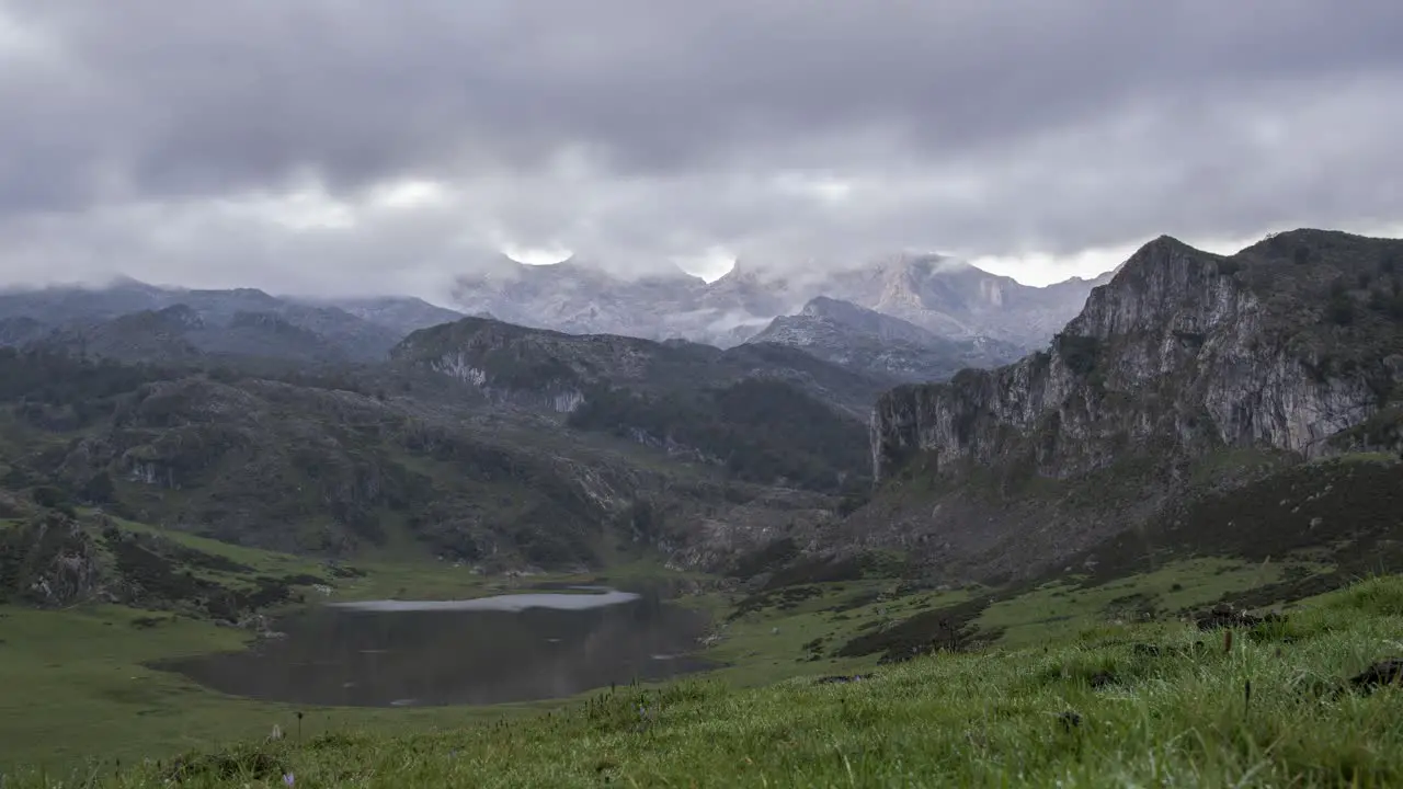 Calm lake surrounded by rocky mountains under gloomy sky