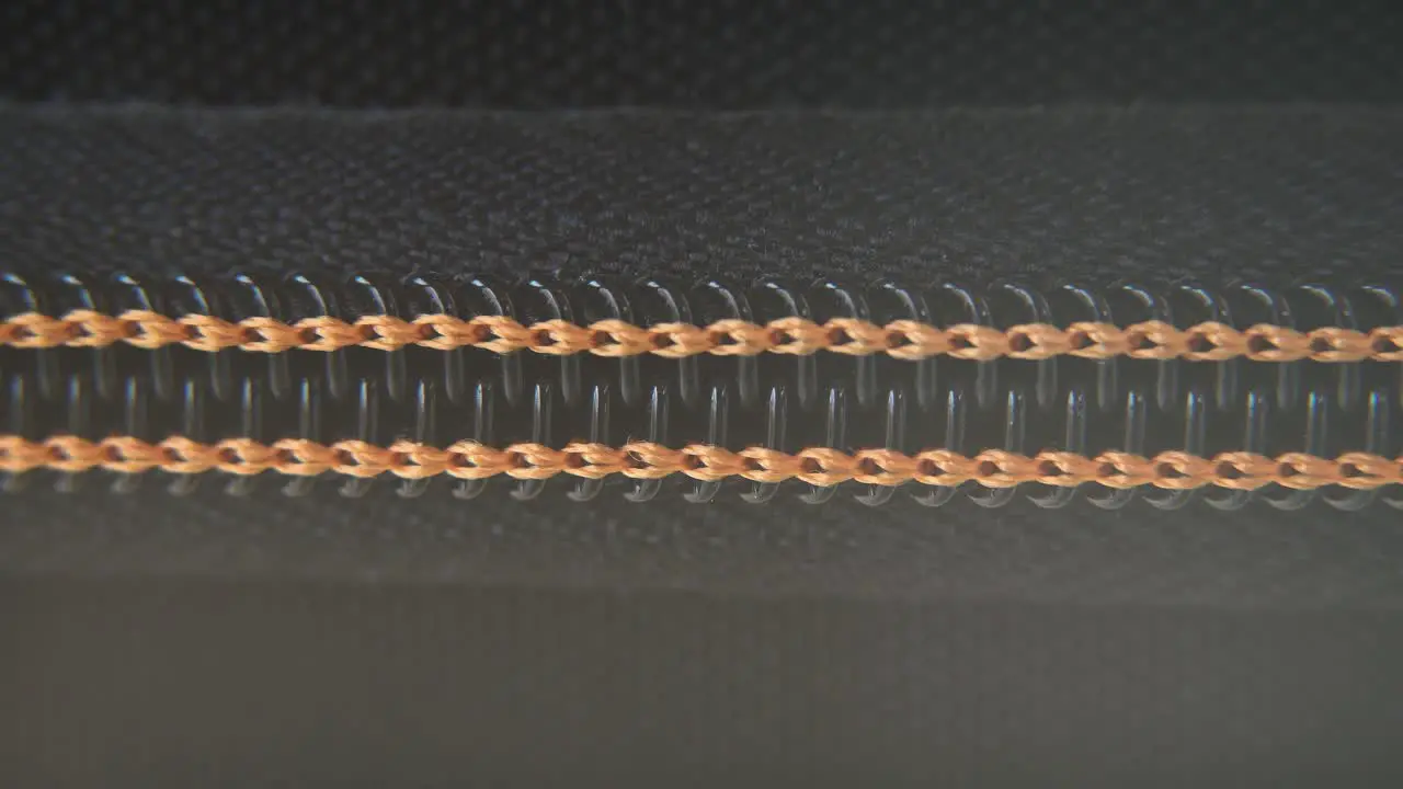 A macro close-up shot of a hard case zipper being opened slowly orange yellow strings metal zip black box photography gear professional studio lighting static 4K video