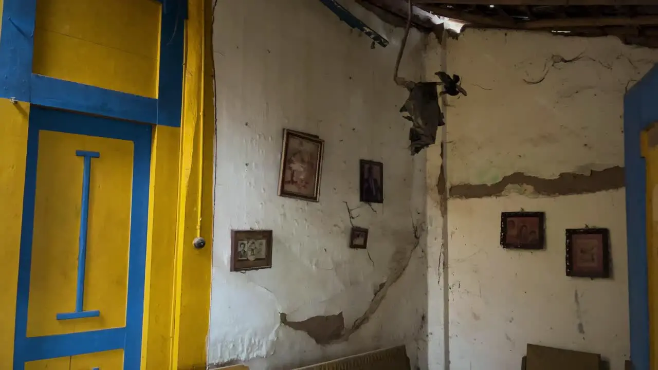 Dark empty scary interior shot of old home with family photos on the damaged wall