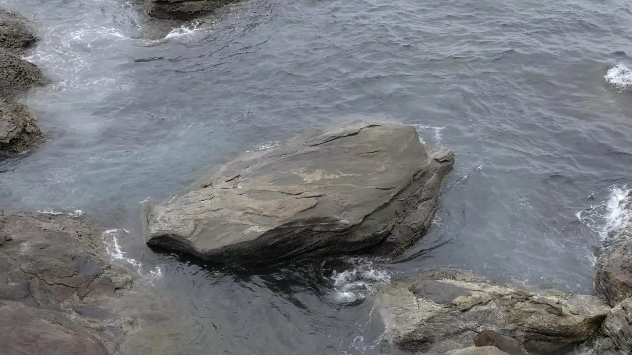 Flowing ocean waters over large rock boulders on coastal shoreline