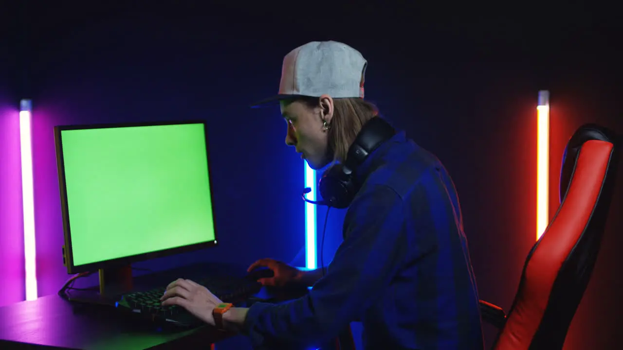 Young Man Playing On The Computer With Chroma Key Screen Then Looks At The Camera And Smiles