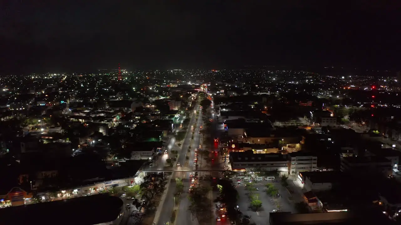 Forwards fly above large town at night Multilane road leading through urban neighbourhood in flat landscape Cancun Mexico