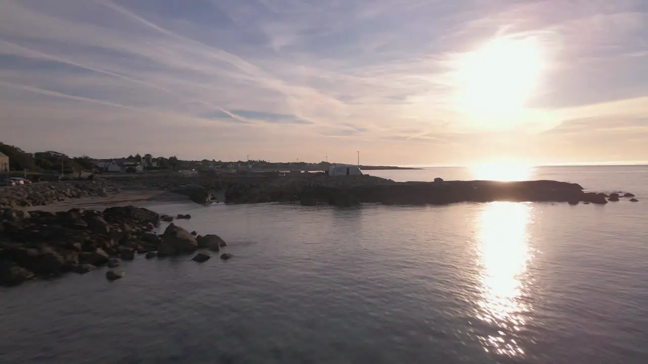 Aerial Drone Footage at seashore in Ireland while crossing shore Rocks During Sunset birds flying around in the water with brilliant sky