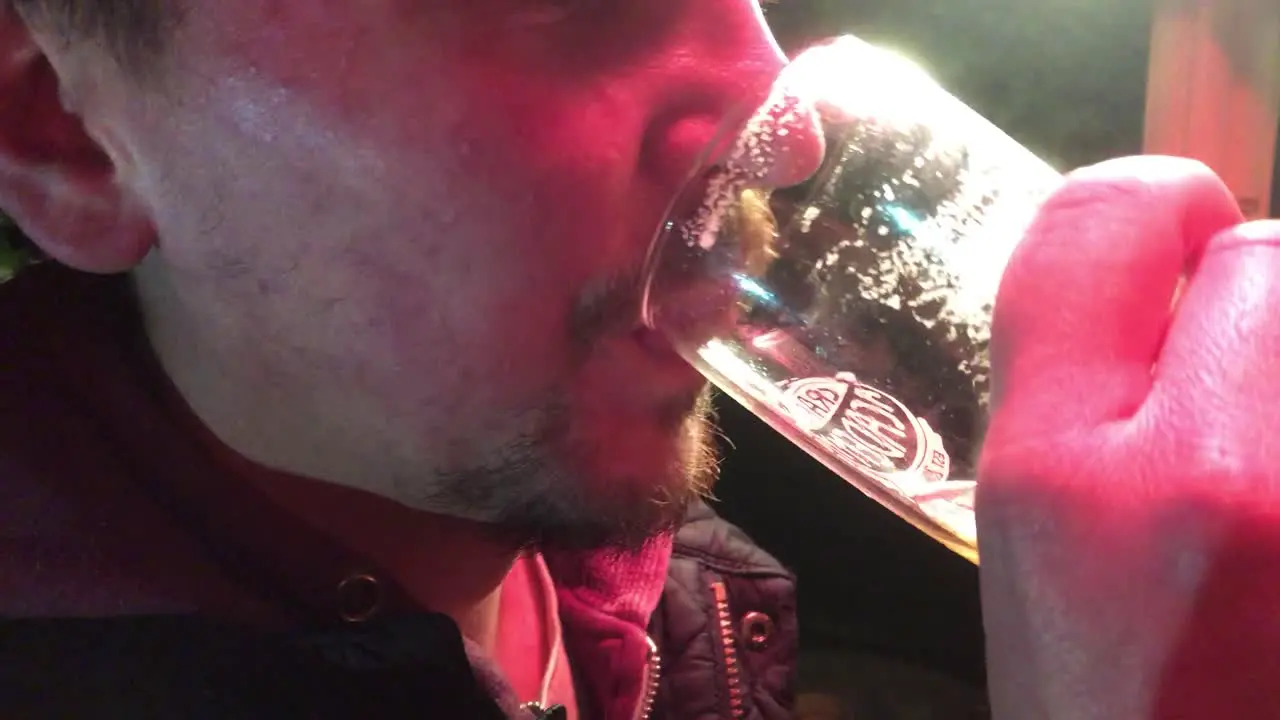 Man drinking a pint of beer in a pub garden at night