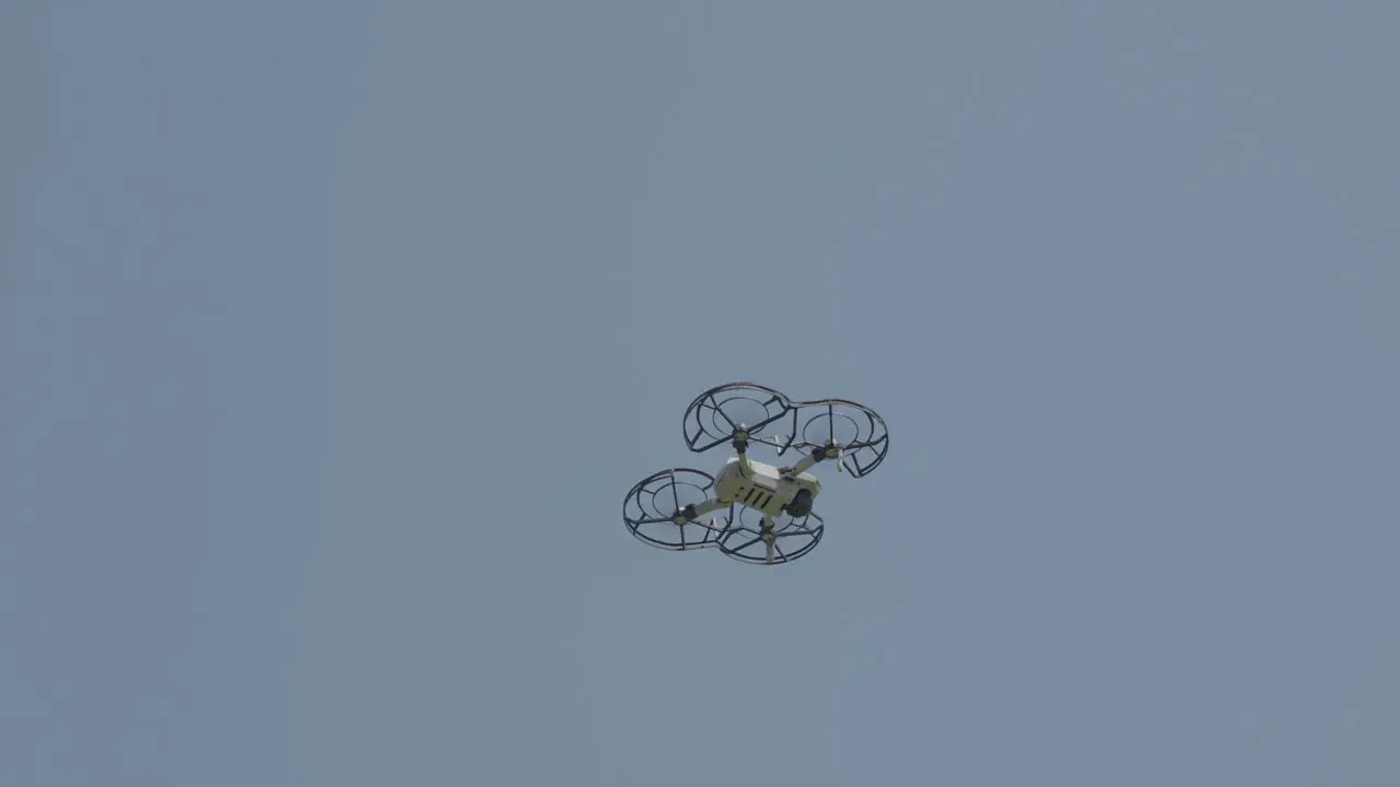 Witness the marvel of modern technology as an individual drone hovers gracefully in the boundless sky on a pristine clear day