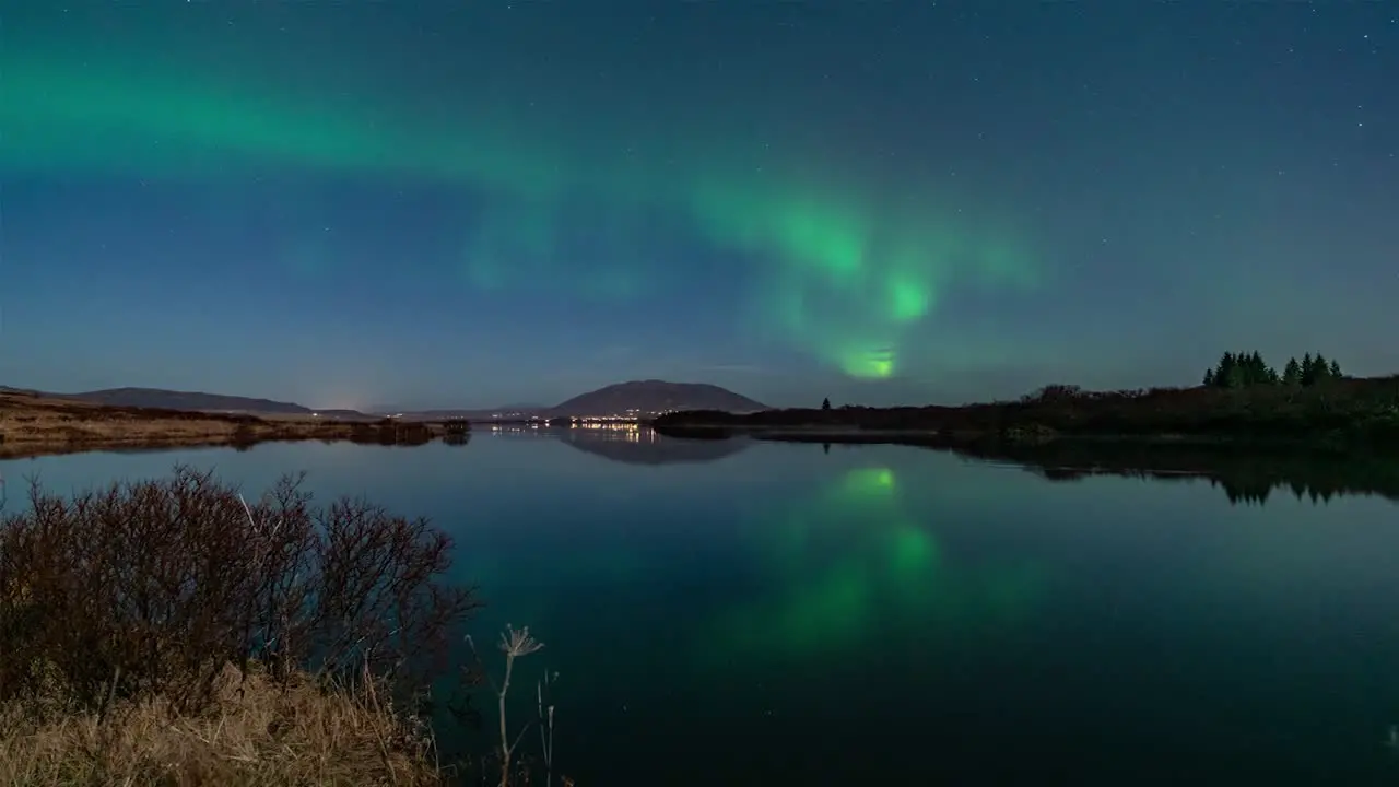 A timelapse video on a still night with Northern lights reflecting in a lake in Iceland