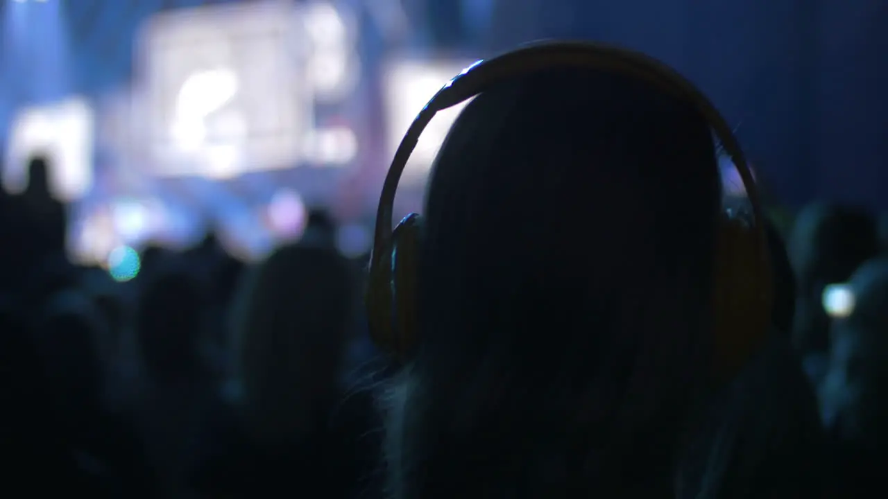 Woman in crowd on the concert puts on headphones