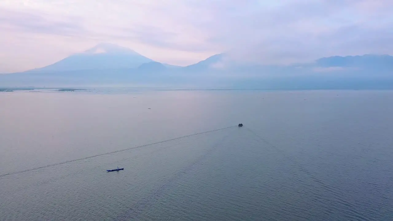 Traditional fisherman boat leaving port in the Morning for fishing with mountain range silhouette in Background Indonesia