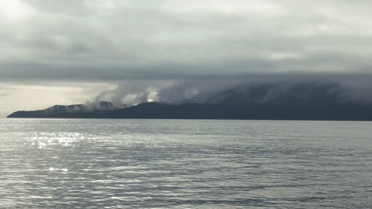 View From Calm Lake Of Fog Clouds Over Mountains In British Columbia Canada On A Moody Weather