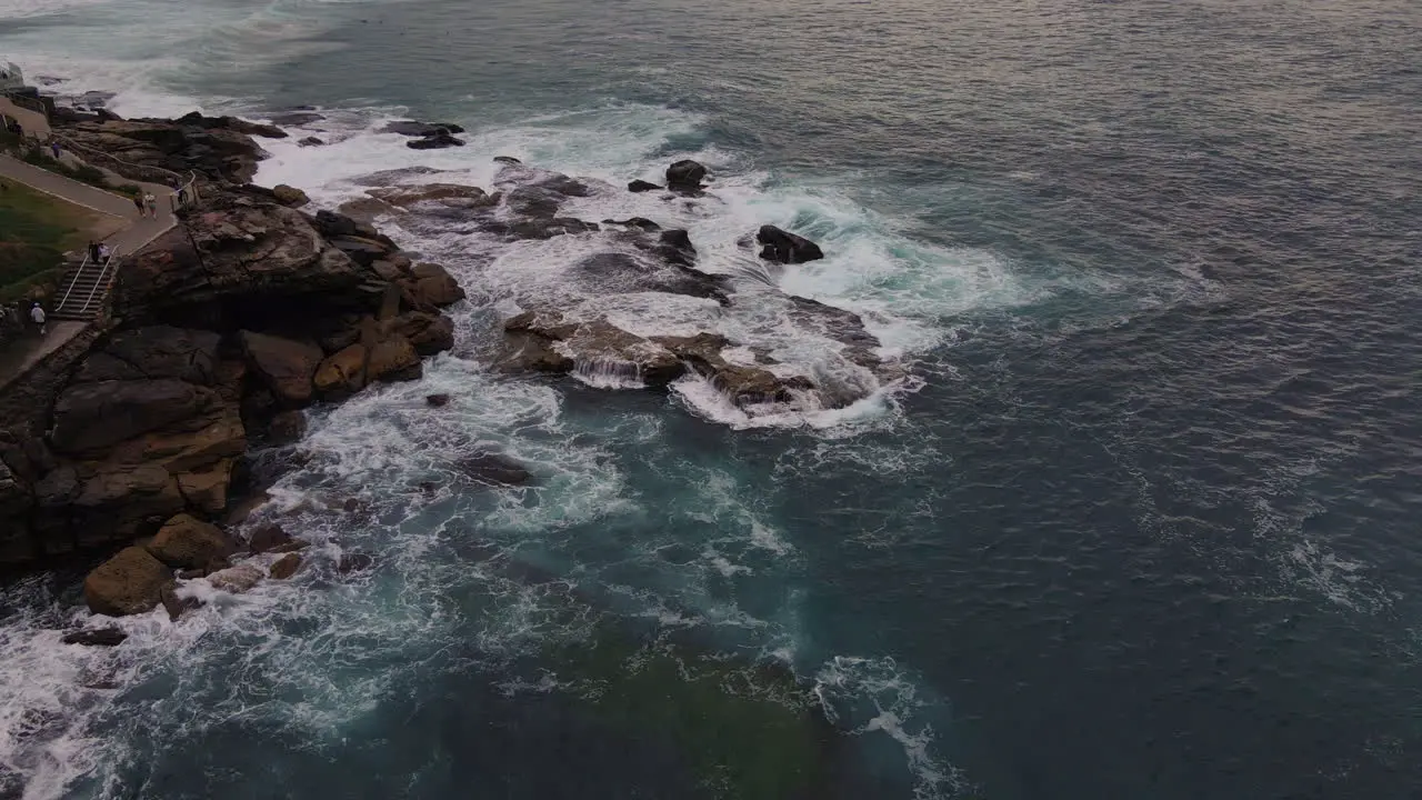 High drone shot of rocks being lapped with waves