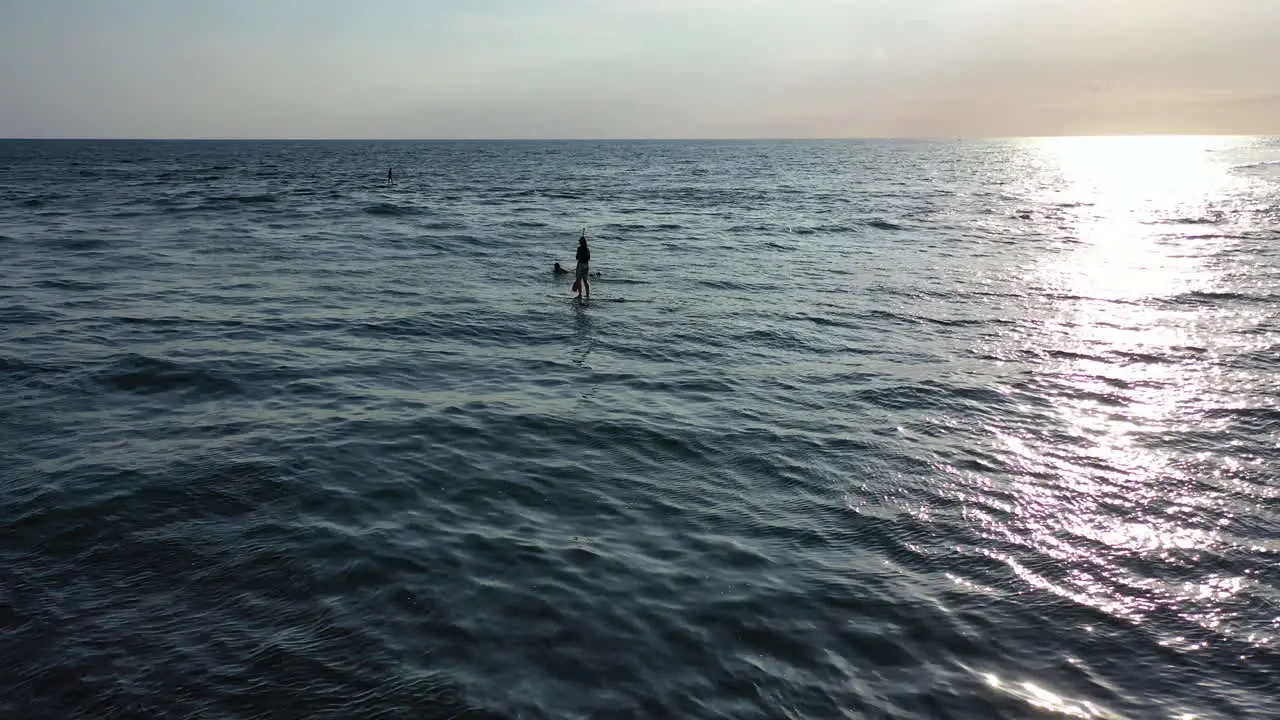 Paddleboarder and a surfer enjoying the calm waters around Reunion Island as the sun sets