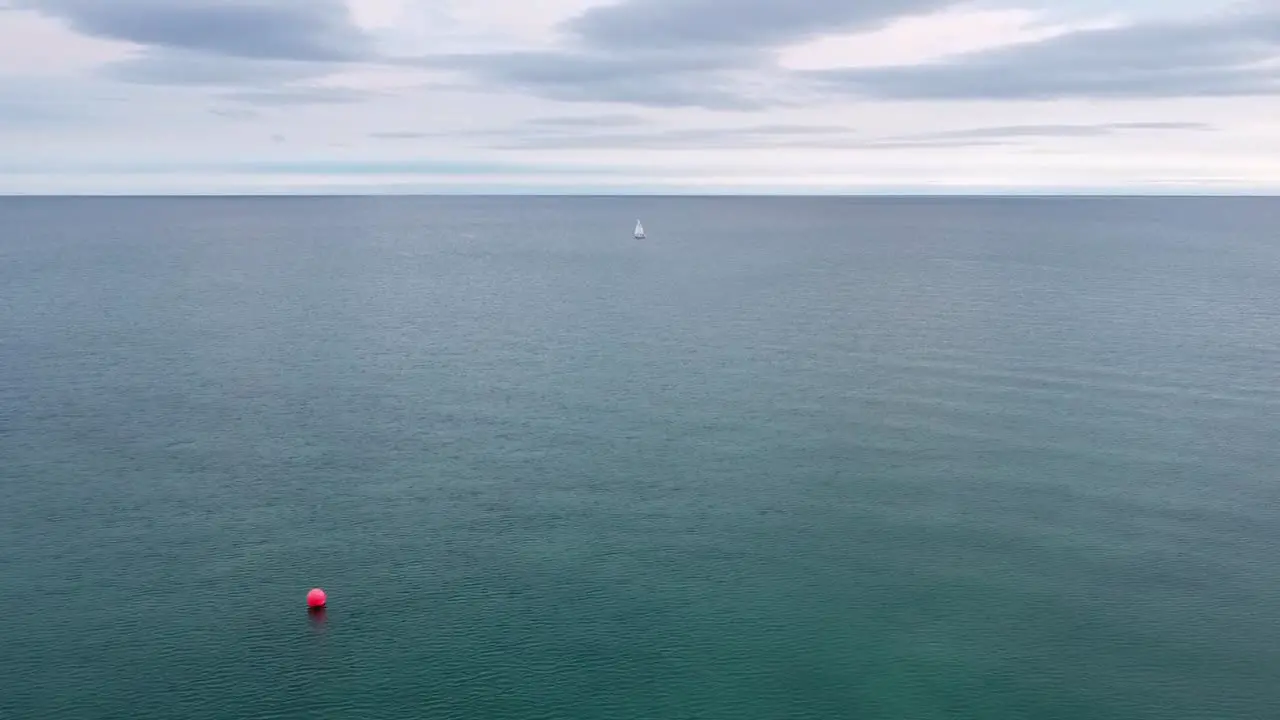 Lone sailboat and red buoy in beautiful clear turquoise blue fresh water