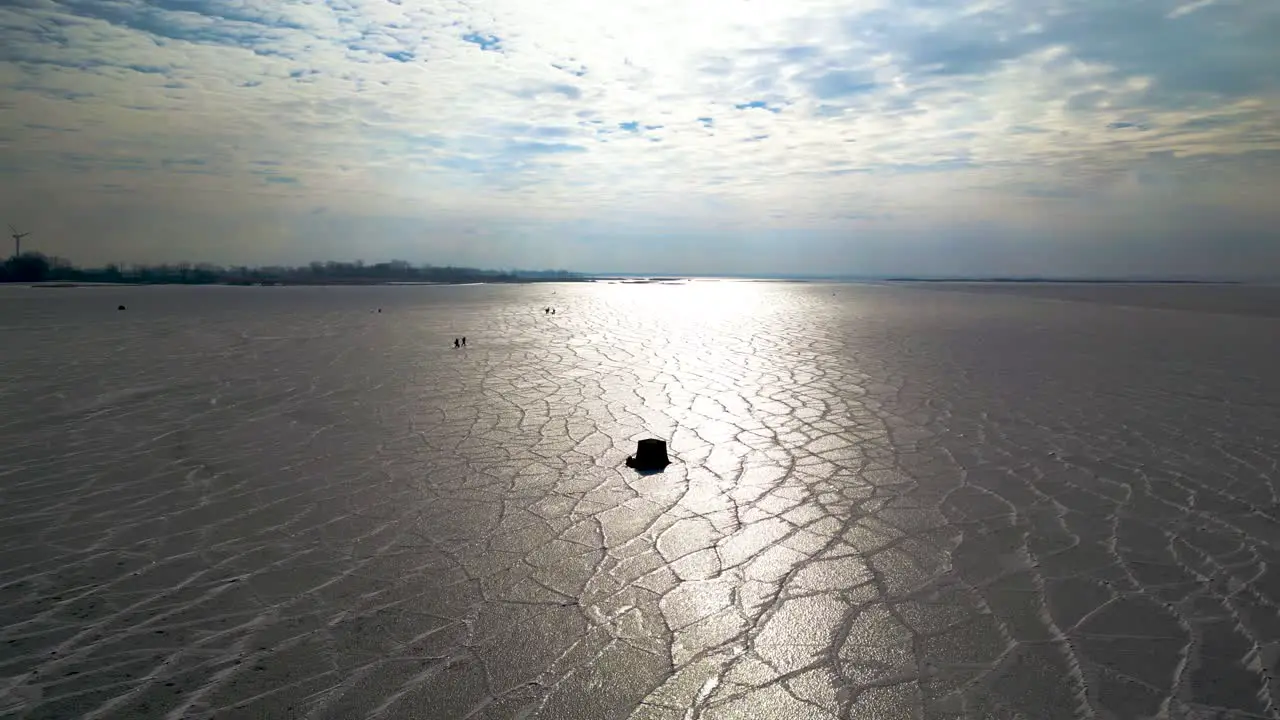 winter fishing tent on frozen lake with sun in the background and texture icy lake Lake St Clair 60fps aerial drone shot