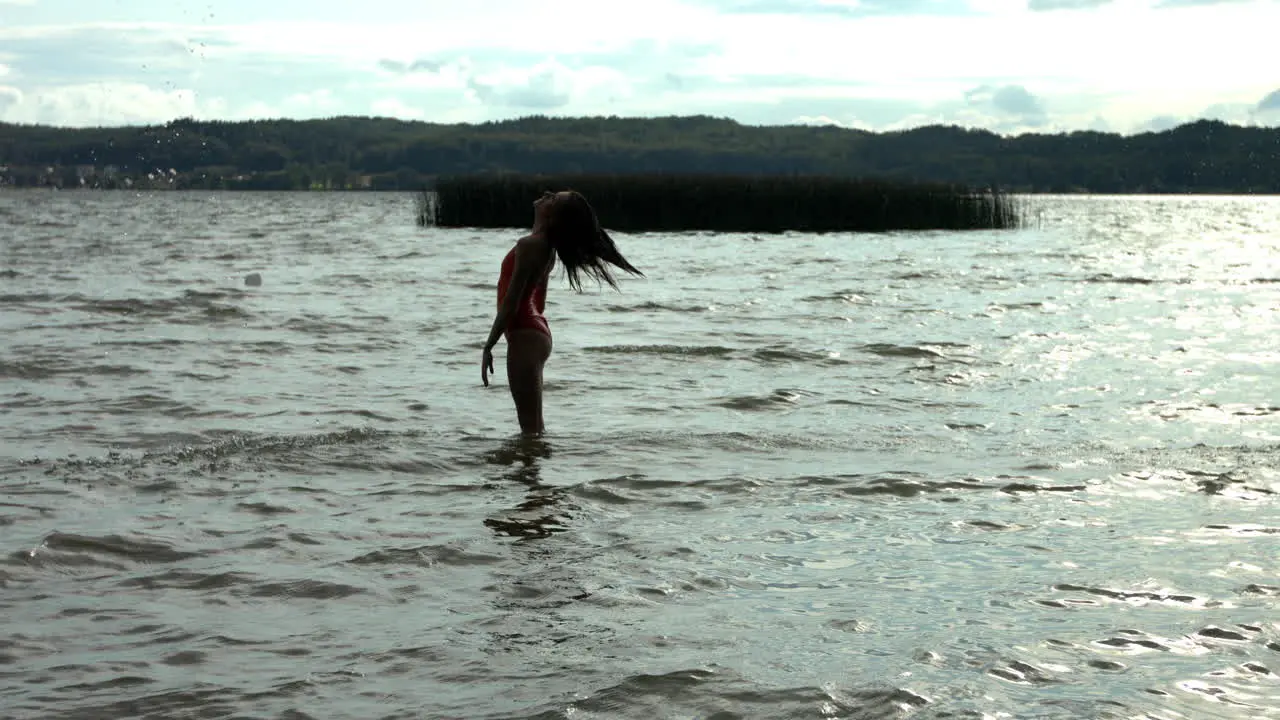 Silhouette of woman throwing own hairs into air in ocean slow motion shot