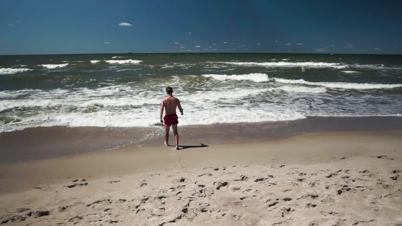 Young man in red shorts goes to sea in a beach-1