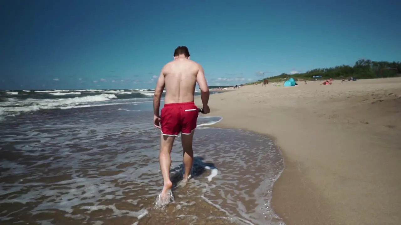 Young man in red shorts walks in a beach by the sea-1