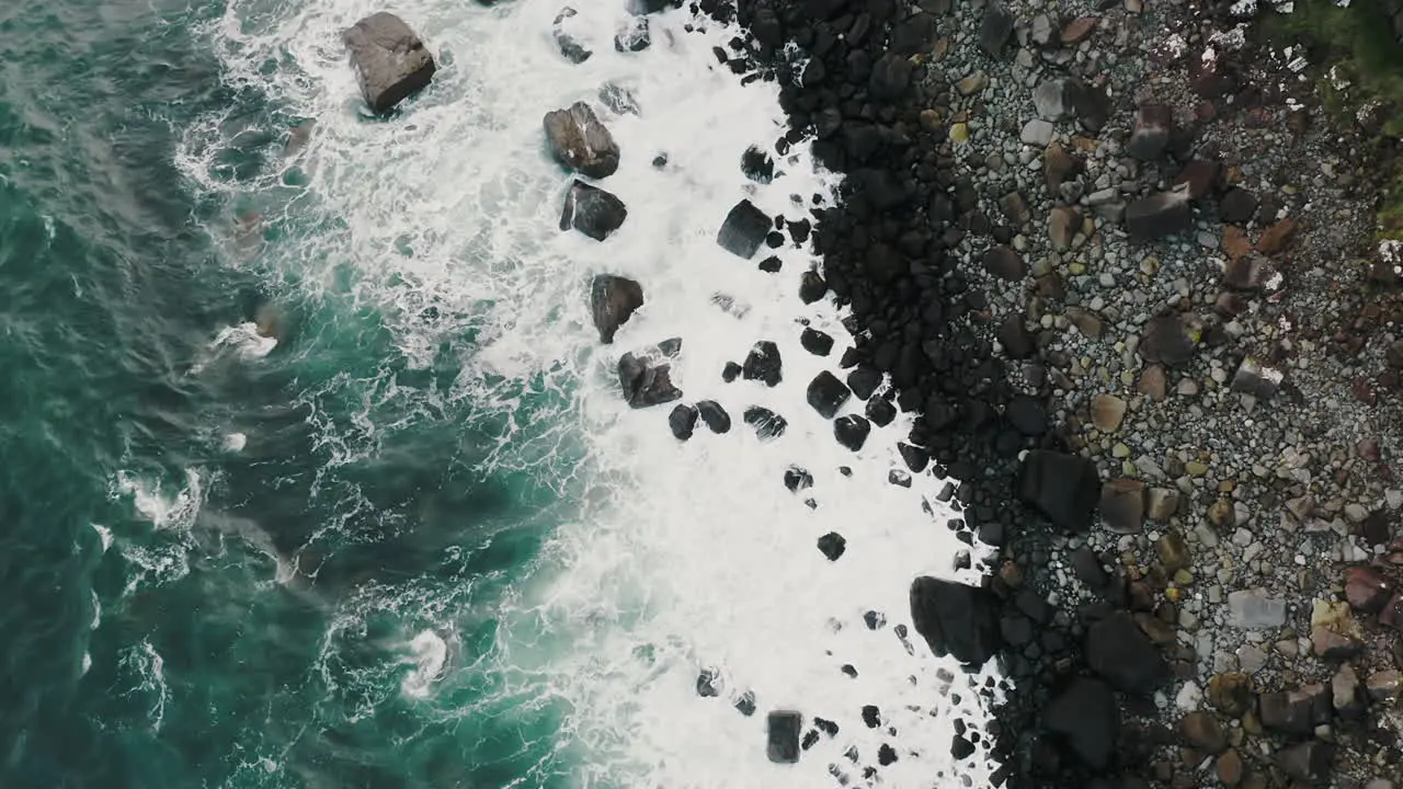 Tilt Up Aerial View of Sea Waves Breaking on Coast Under Breathtaking Rocky Cliffs of Isle of Skye Island Scotland UK