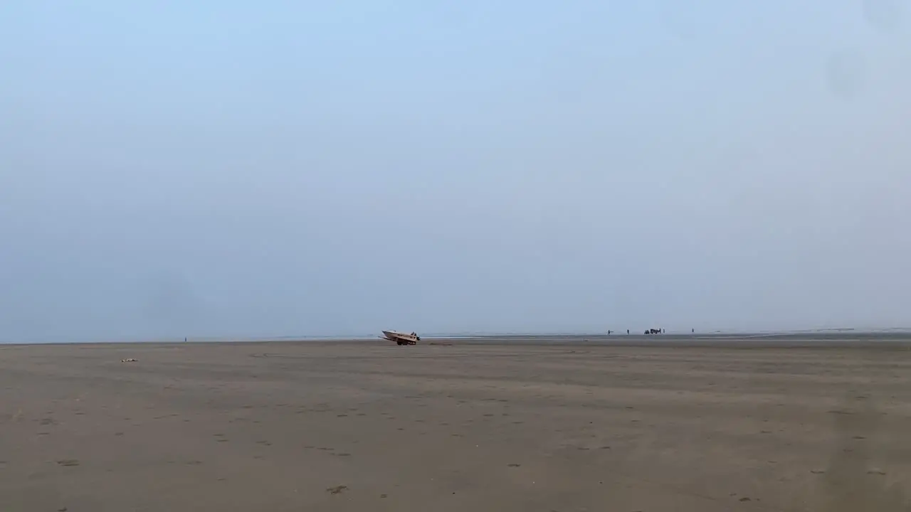 Slow motion shot of the sand in the beach with a boat in a natural background of sky