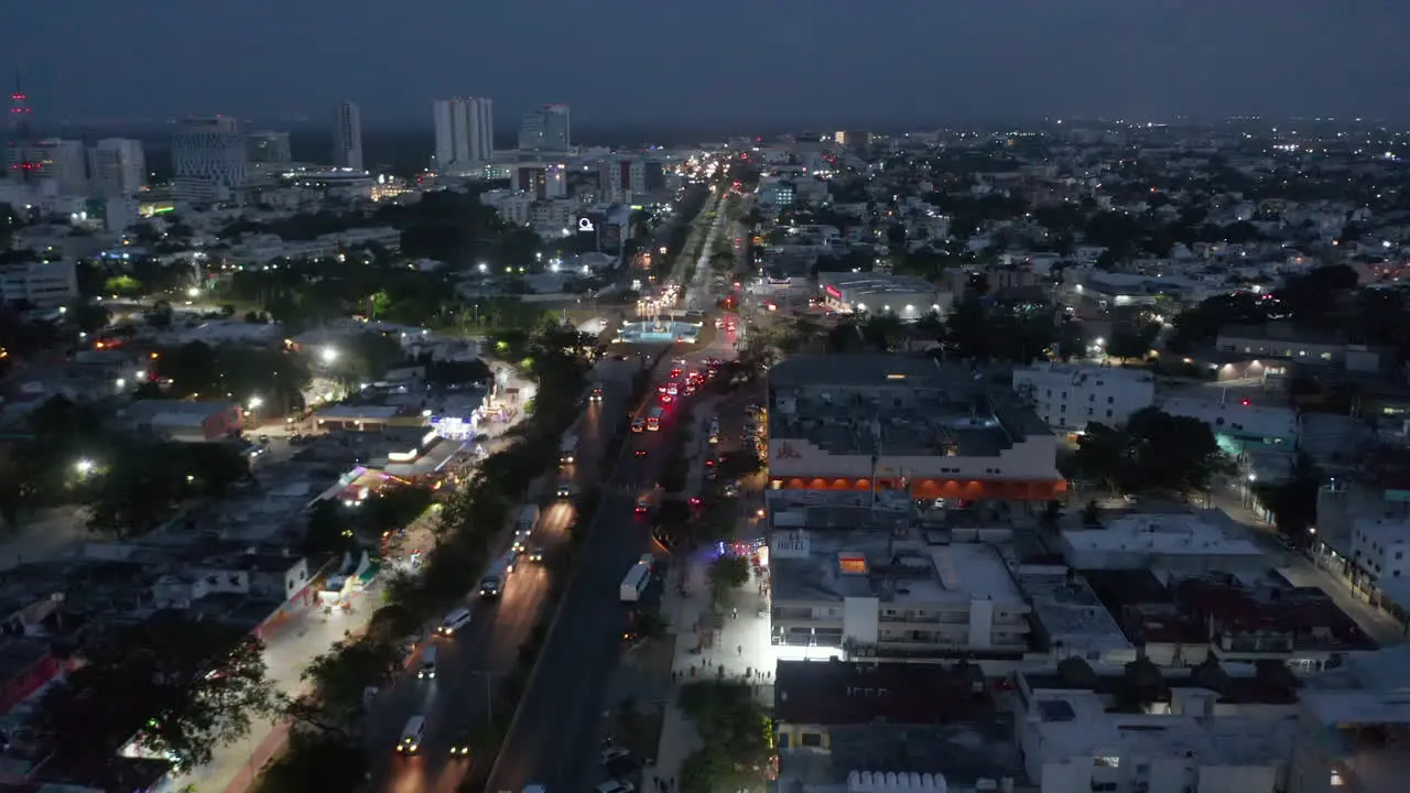 Aerial view of busy road interception in night city Tilt down on Glorieta del Ceviche landmark inside roundabout Cancun Mexico