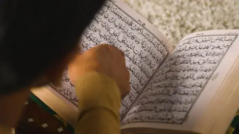 Nahaufnahme Eines Muslimischen Mannes Zu Hause Der Auf Dem Boden Sitzt Und Aus Dem Koran 2 Rezitiert