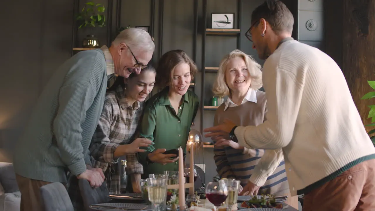 Familia Feliz Mirando Algo Divertido En El Teléfono Móvil Mientras Comen Juntos En Casa