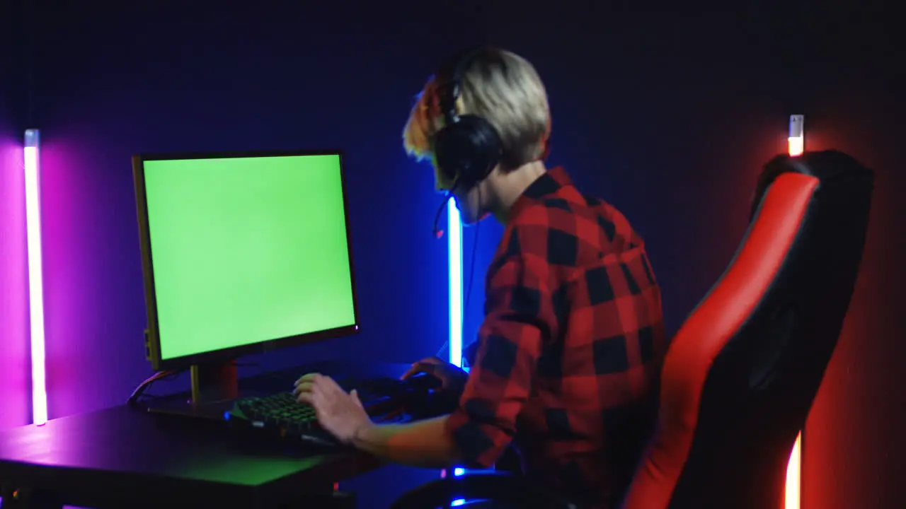 Young Woman Playing On The Computer With Chroma Key Screen In A Room With Colorful Neon Lamps On The Wall 1