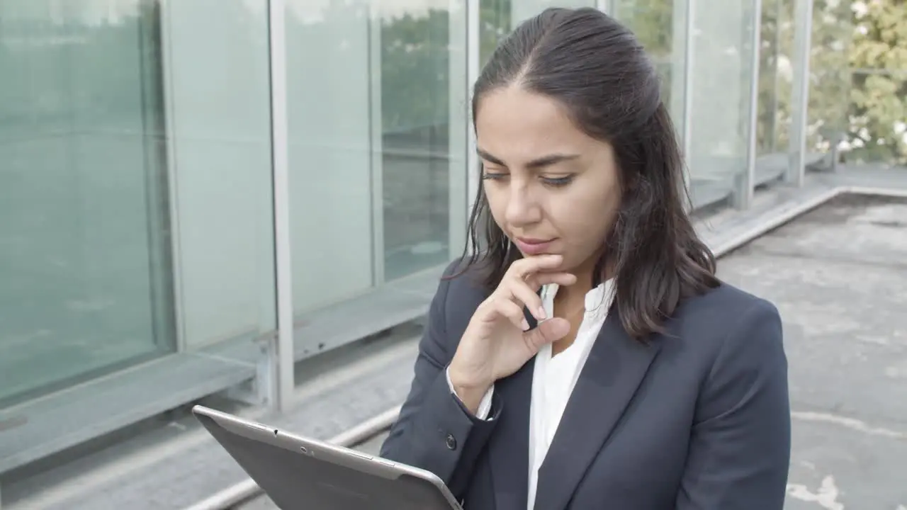 Dolly Shot Of A Pensive Young Business Lady Using Online App On Tablet For Work While Walking Outside