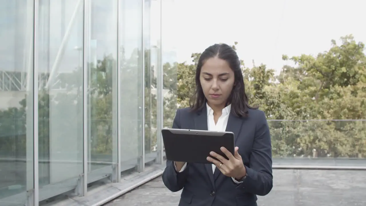 Dolly Shot Of A Focused Latin Businesswoman In Suit Using Tablet For Work While Walking Outside