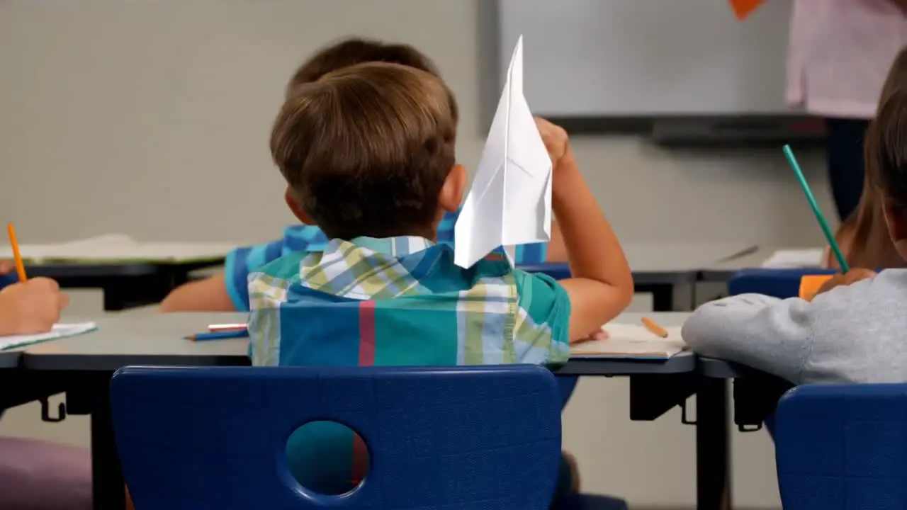 Junge Wirft Papierflieger Während Lehrer Im Klassenzimmer Unterrichtet