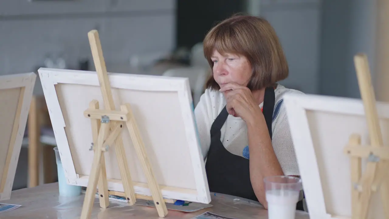 An elderly woman draws a picture in a painting course