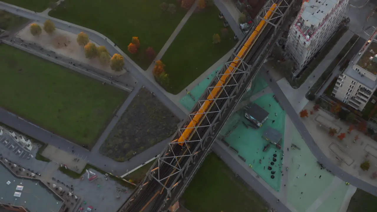 Iconic Typical Berlin Subway Train in yellow color passing a bridge through Public Park in Germany Aerial Birds Eye Overhead Top Down View