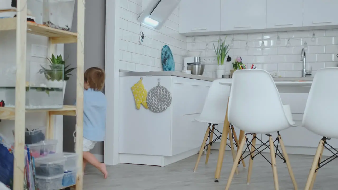 Two children jump and enjoy running in the house in the kitchen