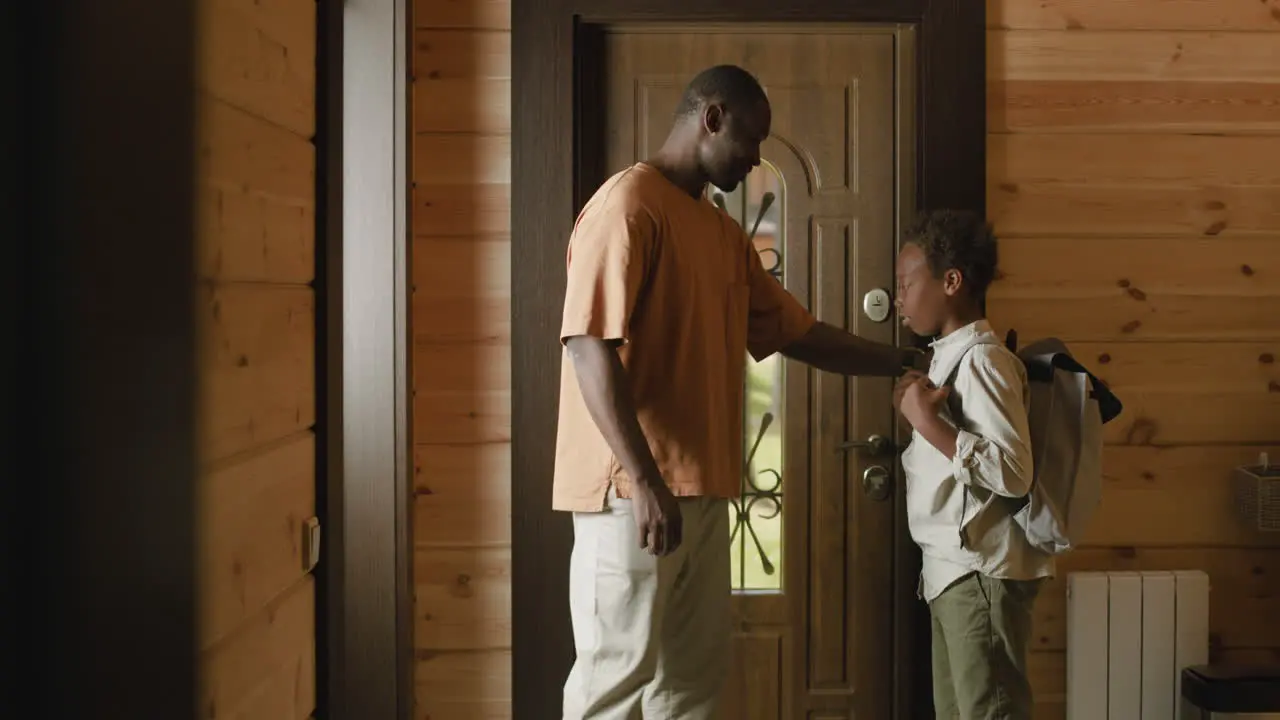 Loving Dad Helping His Son To Put On School Bag Then Opening Door And The Boy Leaving Home