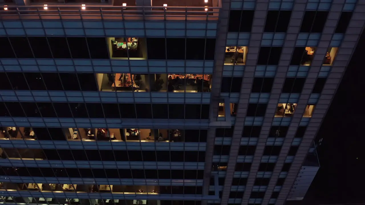 Descending footage along wall of tall office building People working overtime in evening Warsaw Poland