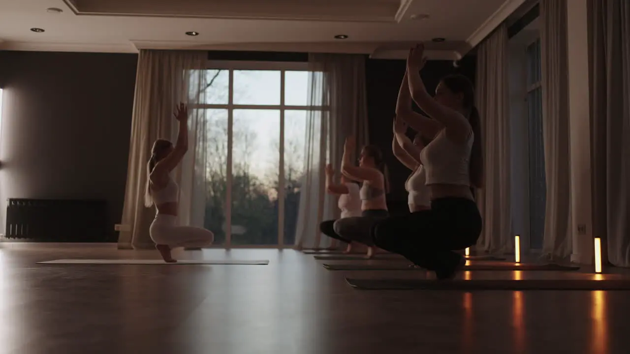 A group of women practice yoga under the strict guidance of an instructor in slow motion and sunlight at sunrise