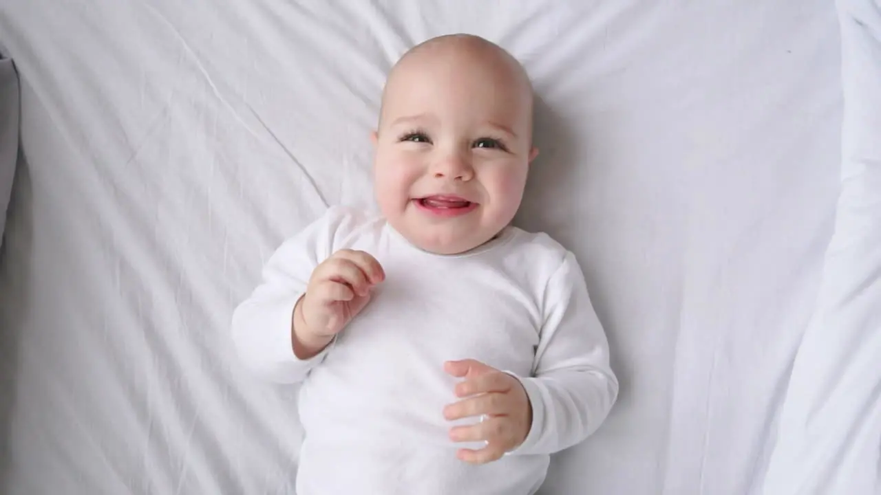 Cute little baby lying on bed top view