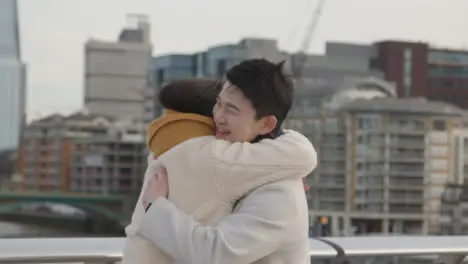 Young Asian Couple Meeting And Hugging On Millennium Bridge In London UK