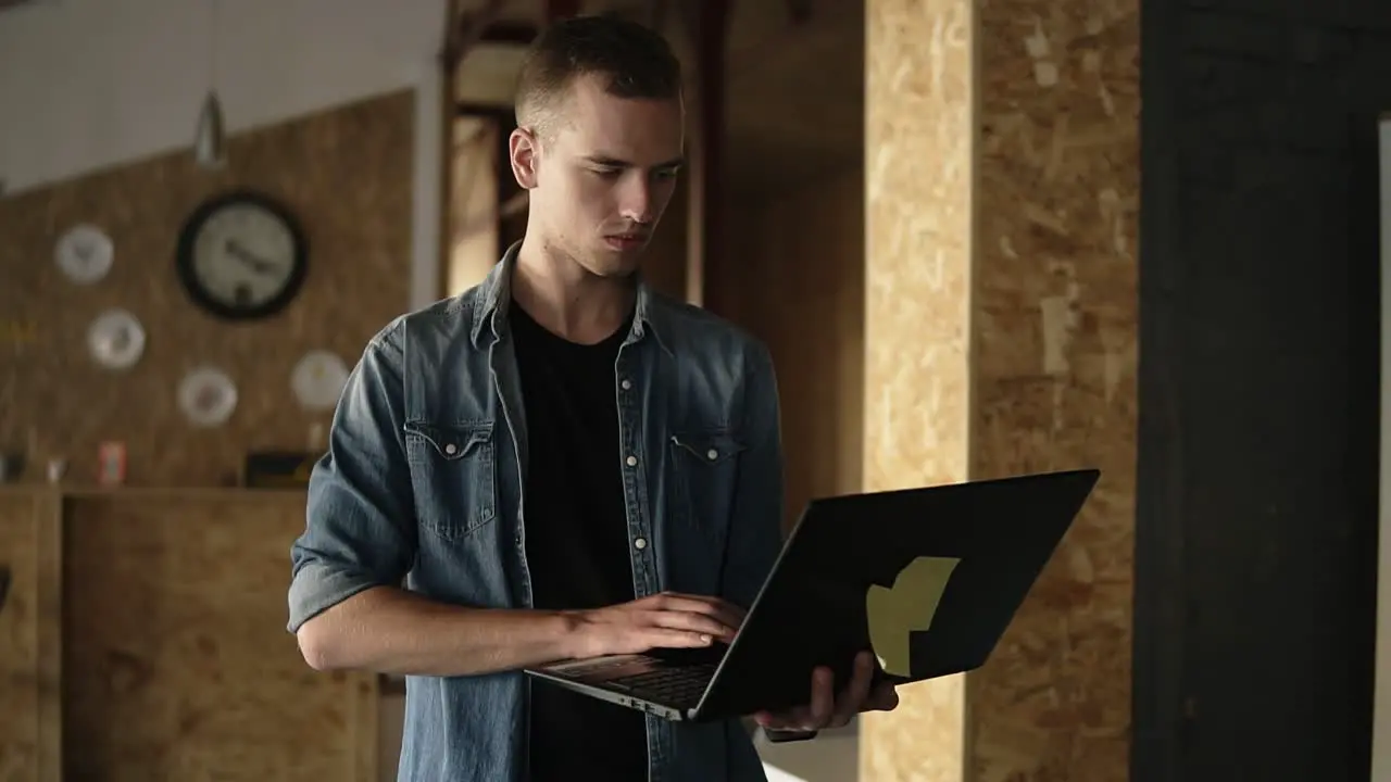 Attractive Concentrated Young Business Man Is Walking With A Laptop In His Hand And Typing