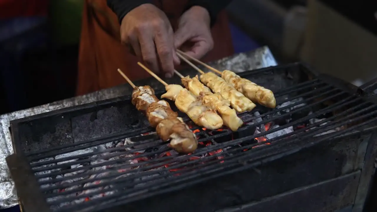 A vendor in Bangkok is grilling traditional Thai skewers for street food