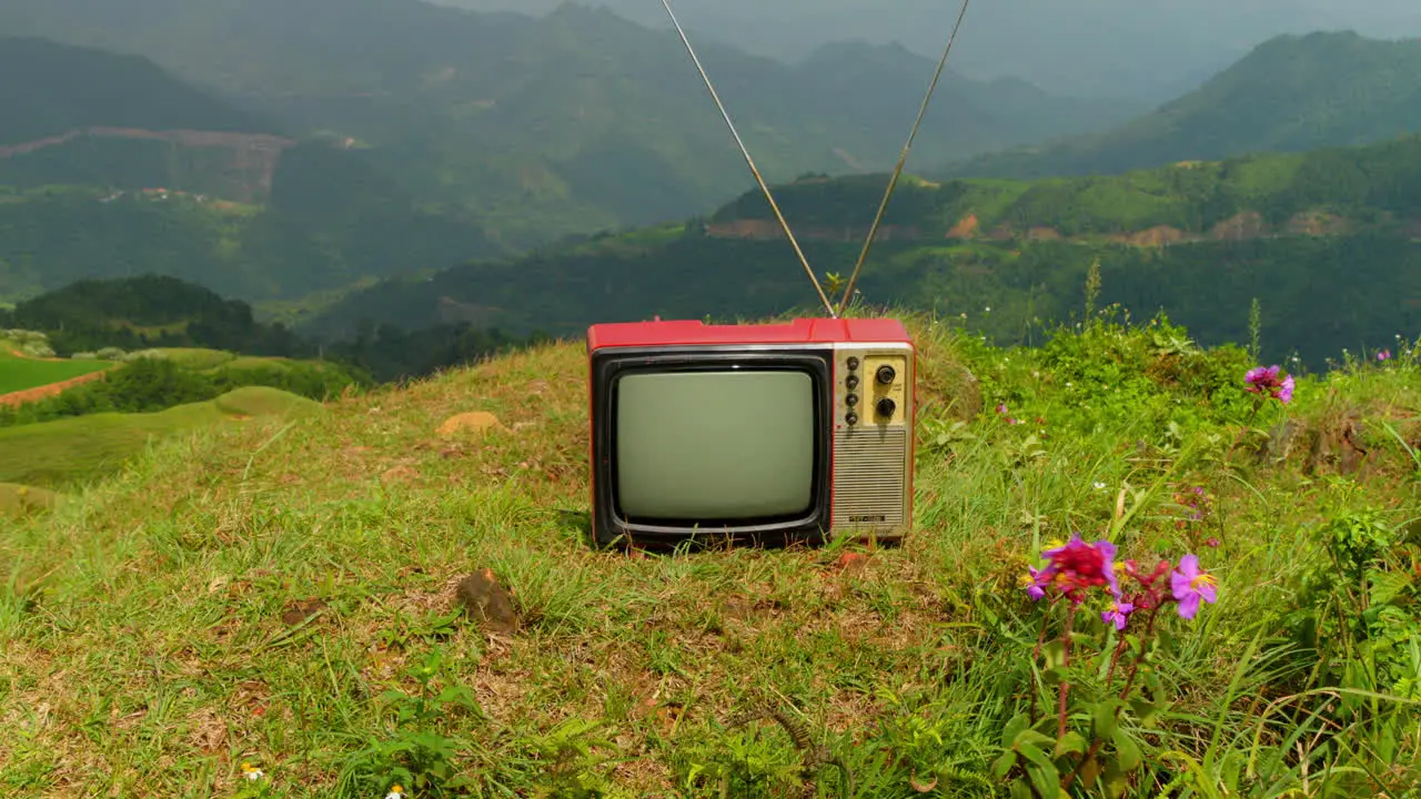 Abstract video of old television on green mountain top technology nature fusion