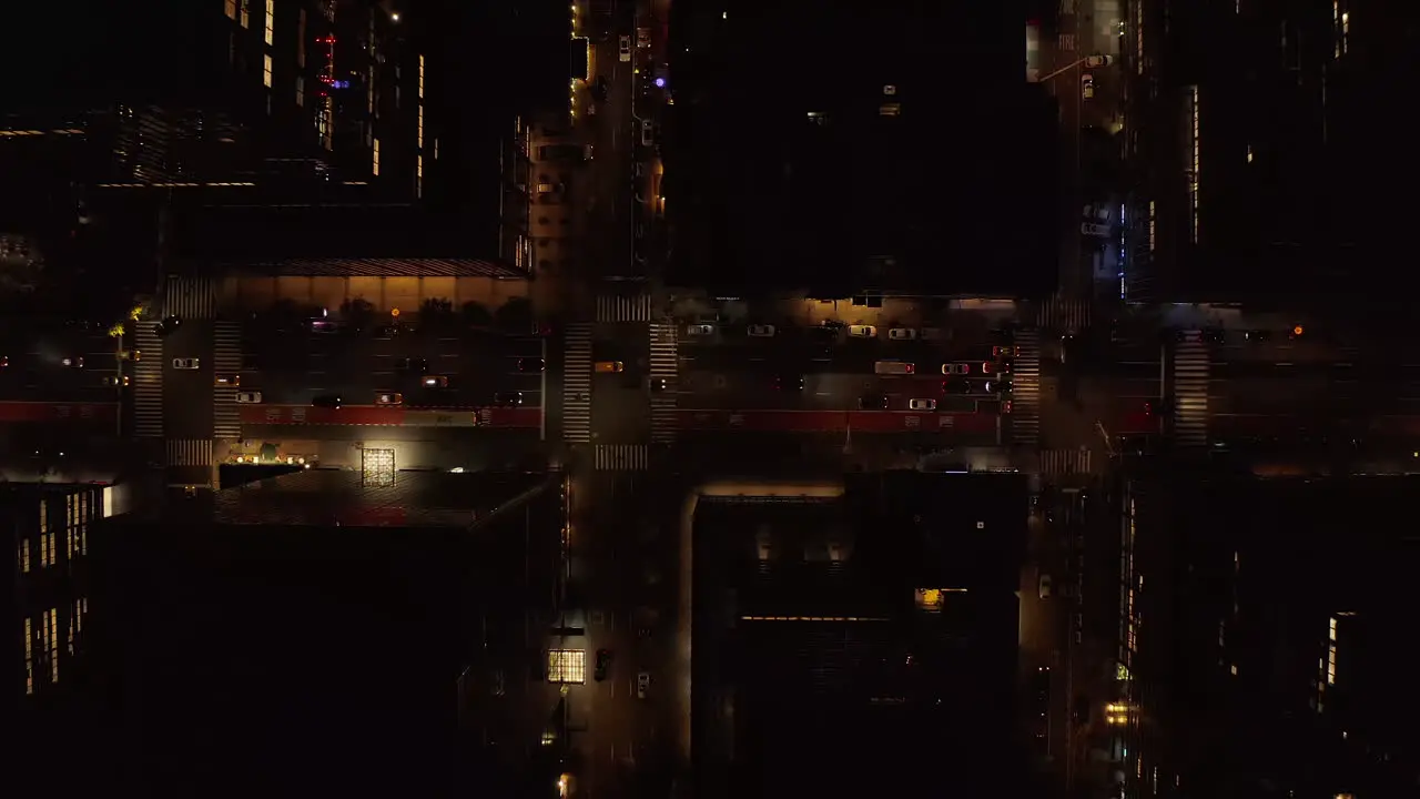 Aerial birds eye overhead top down panning view of busy multilane one way street at night Vehicles driving between high rise buildings Manhattan New York City USA