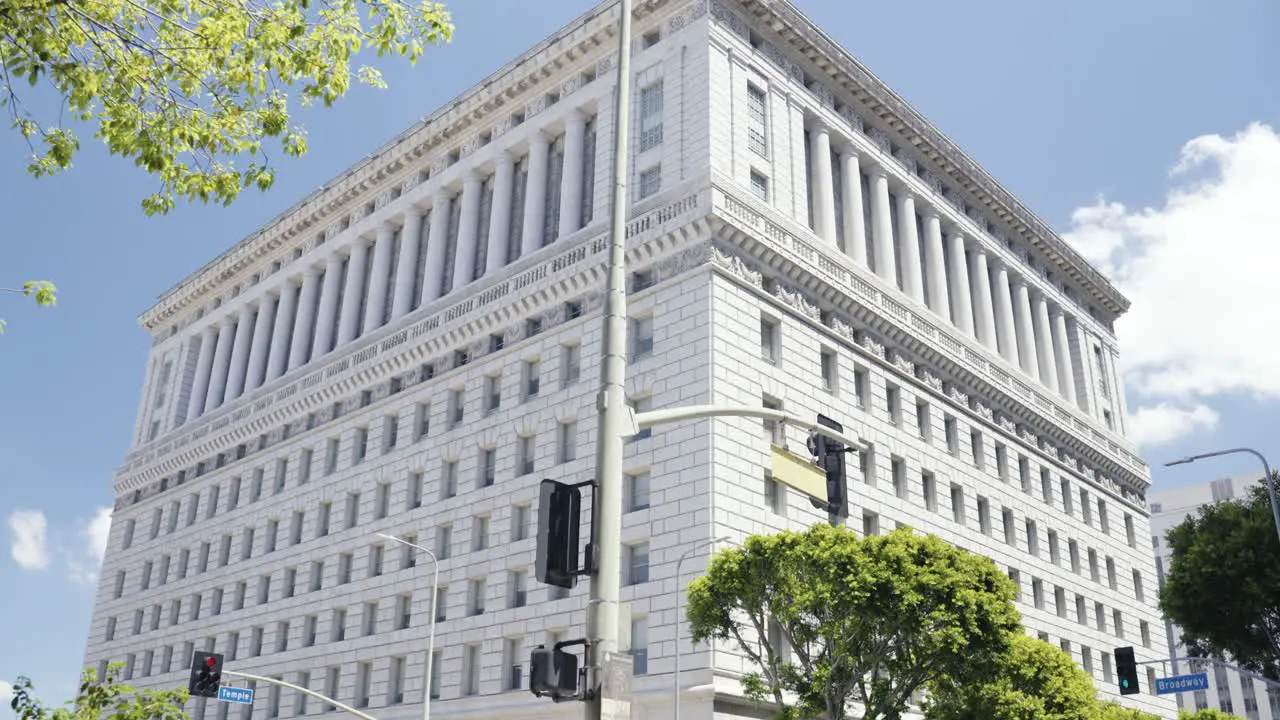 View onto the Hall of Justice in Los Angeles California during Summer time with people and cars crossing the streets natural organic pan camera movement