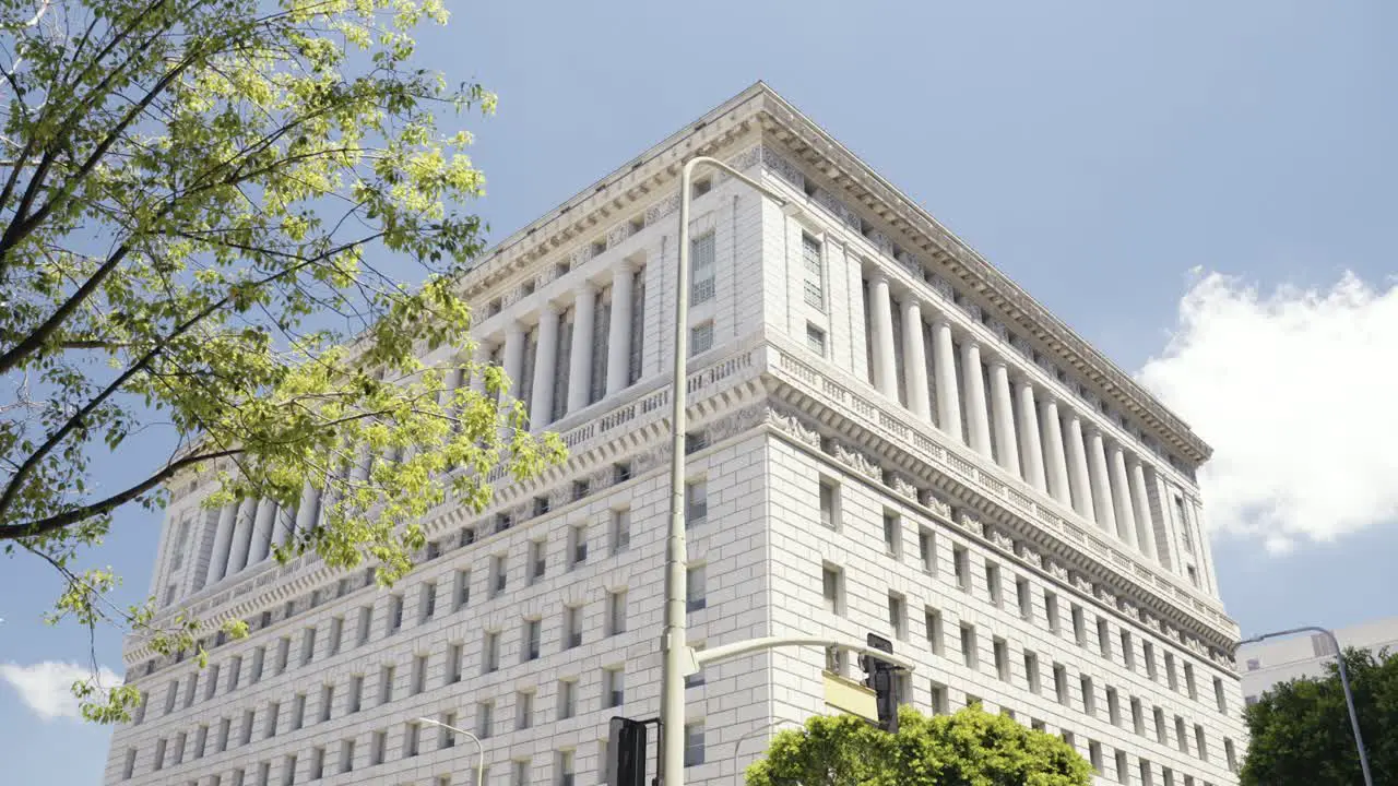 View onto the Hall of Justice in Los Angeles California during Summer time with cars driving along paning camera movement