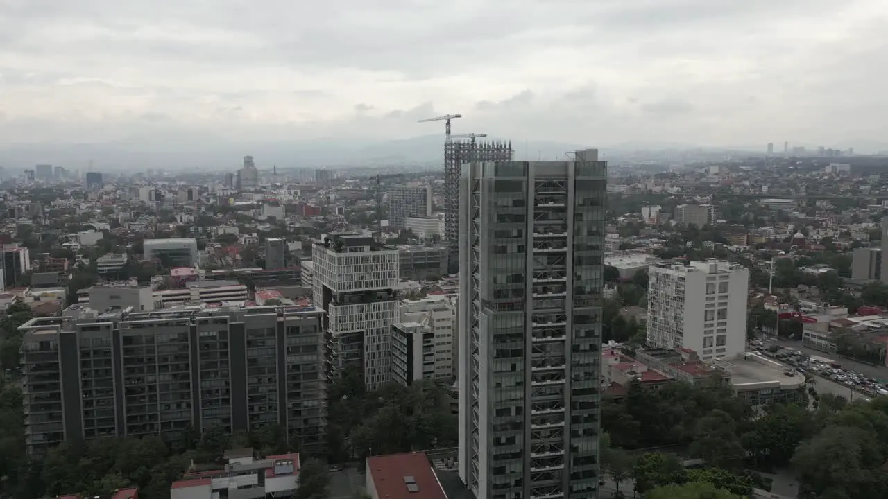 Aerial orbits urban high-rise skyscrapers in hazy Mexico City skyline